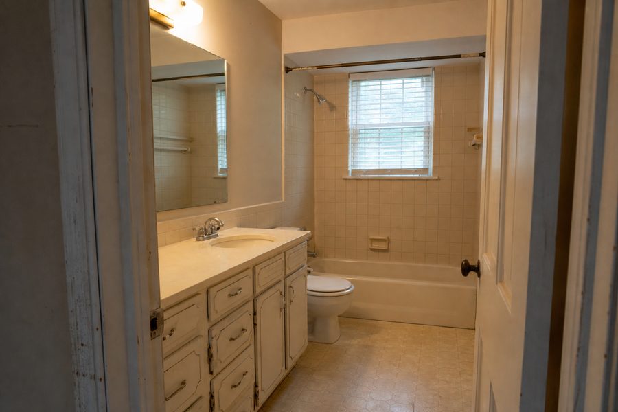 Before bathroom remodeling photo showing dated vanity tile tub surround flooring lighting and trim for Cerpa Construction LLC renovation.
